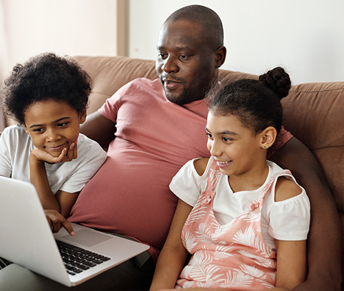 father and children watching a computer
