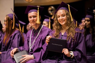 girl and boy graduates showing their diplomas