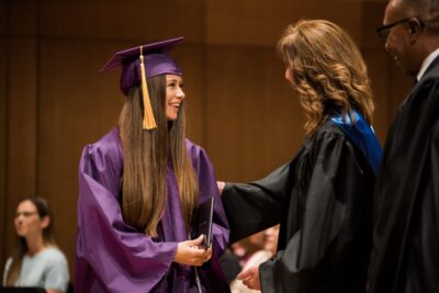 Graduate girl receiving diploma from her teachers
