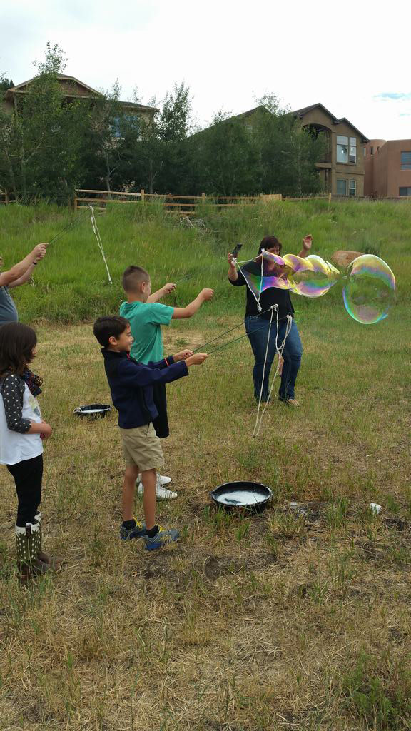 children playing with big bubbles outside a house